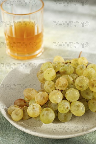 A branch of white grapes, on a gray plate, with a glass of white wine, top view, natural light,