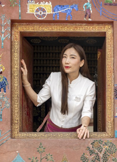 Woman looks out the window at Wat Xieng Thong, Luang Prabang, Laos, Asia