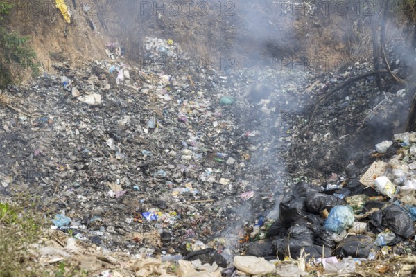 Coking rubbish dump, rubbish pit with waste and plastic rubbish, karst landscape near Vang Vieng,