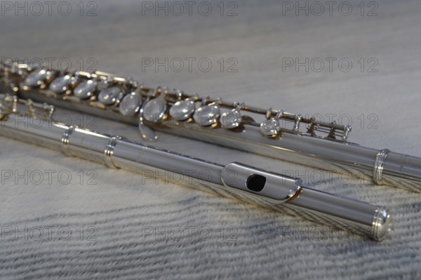 Silver transverse flute with keys on a beige background