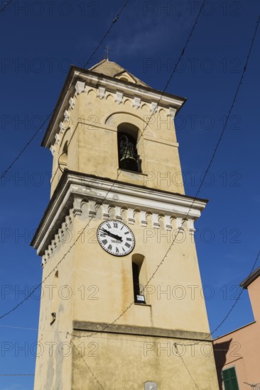 Yellow stucco cladded bell tower with white and black clock face in late summer, Manarola village,