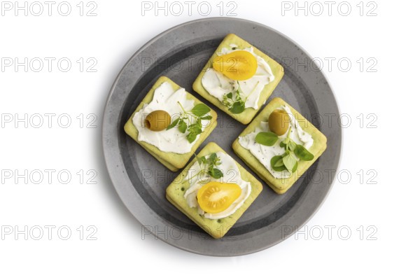 Green cracker sandwiches with cream cheese and cherry tomatoes on gray plate isolated on white