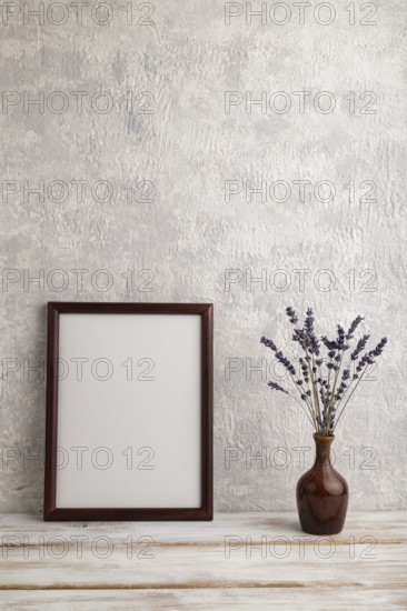 Brown wooden frame mockup with lavender in ceramic vase on gray concrete background. Blank,