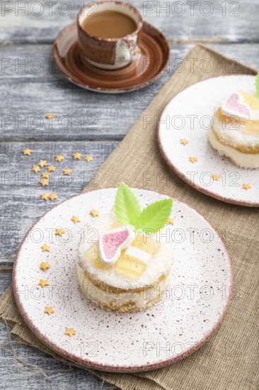 Decorated cake with milk and coconut cream with cup of coffee on a gray wooden background and linen