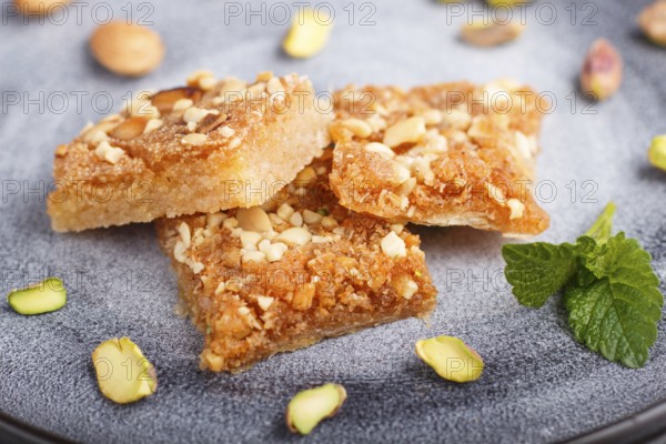 Traditional arabic sweets in gray ceramic plate on a gray concrete background. side view, close up,