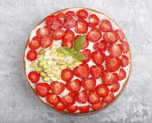 Homemade cake with yoghurt cream, strawberry and pistachio on a gray concrete background. top view.
