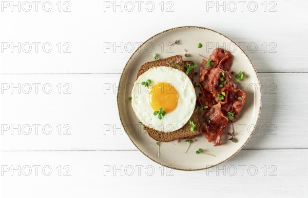 Breakfast, fried egg with bacon, micro-green, on a light background, no people, selective focus