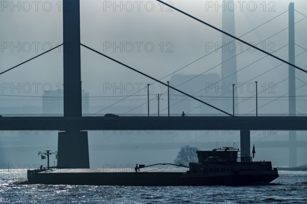 Dense fog slowly lifting, cargo ships on the Rhine near Düsseldorf, in front the Oberkassler