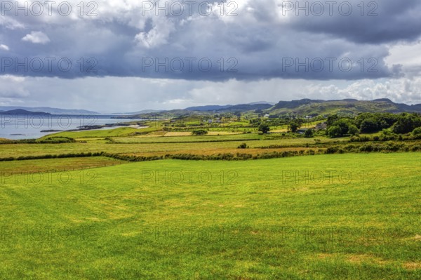 Extensive coastal landscape with sea, meadows and cloudy skies, near the Great Pollet Sea Arch