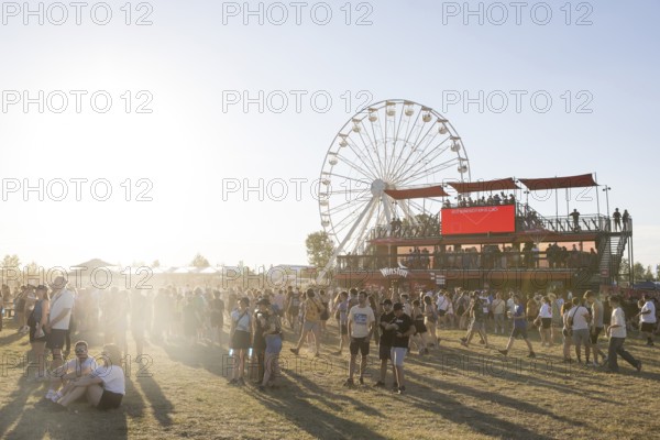 Festival visitors in front of the Ferris wheel and the vantage point of a tobacco vendor at the