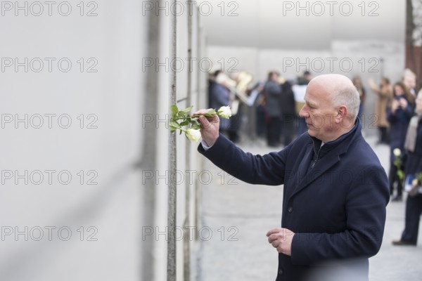 Kai Wegner (Governing Mayor of Berlin) sticks a rose into the Wall at the central commemorative