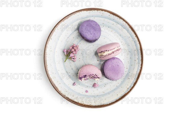 Purple macarons or macaroons cakes on blue plate isolated on white background. Top view, flat lay,