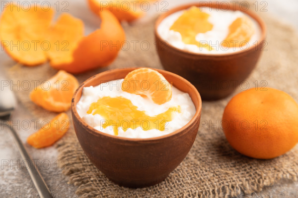 Grained cottage cheese with tangerine jam on brown concrete background and linen textile. side