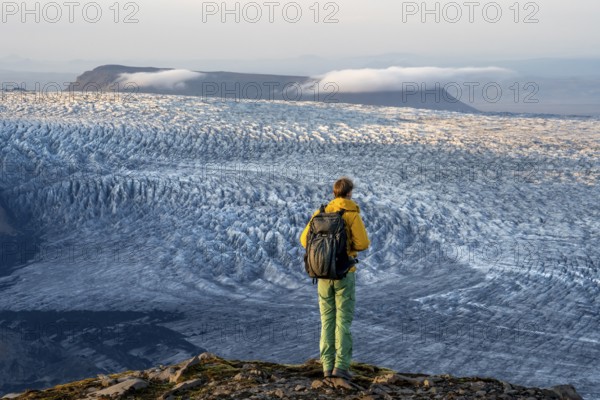 Young man, tourist in front of impressive glacier, in the evening light, glacier tongues