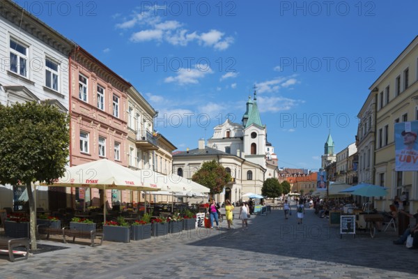 Lively historic street with church, cafés and passers-by under a blue sky, Church of the Holy