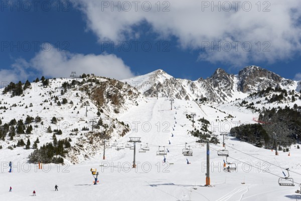Skigebiet in Andorra mit mehreren Liften, Pisten und Skifahrern vor einer schneebedeckten