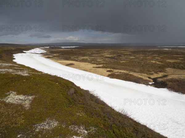 Rain clouds sweeping over tundra landscape, with snow remains in a small valley, Varanger National