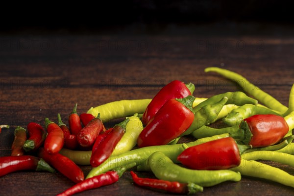 Green and red peppers scattered on a dark wooden surface, food photography