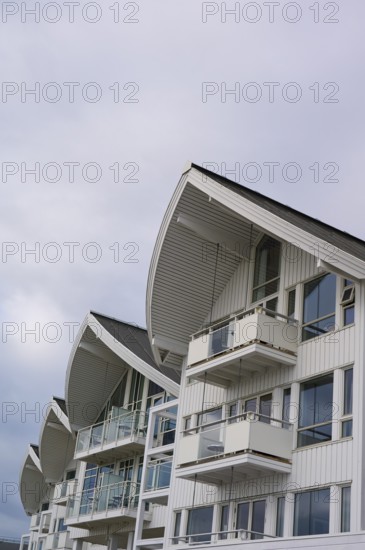 A modern residential building with several balconies and glass fronts under a cloudy sky, Molde,