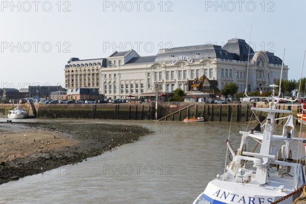 Large historic riverside building with boats in the foreground, Casino Barrière, casino,