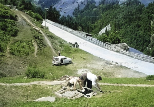 Men making tea and food, British Austin Cambridge A40 car in Austria, overland drive adventure