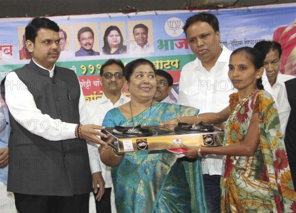 Maharashtra Chief Minister Devendra Fadnavis (L) distributes gas stoves to underpriviledged women