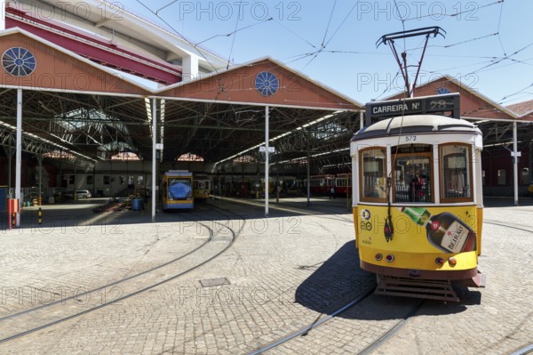 Historic yellow tram, Eléctrico, line 28 in front of tram depot and repair shop, Lisbon, Portugal,