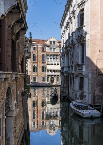 Gondola travelling through a small canal, reflection, Venice, Italy, Europe