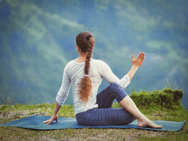 Hatha yoga outdoors, sporty fit woman doing yoga asana Parivrtta Marichyasana (or ardha