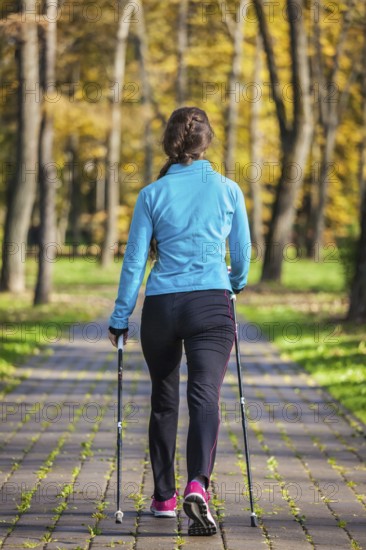 Nordic walking adventure and exercising concept, woman hiking withnordic walking poles in park