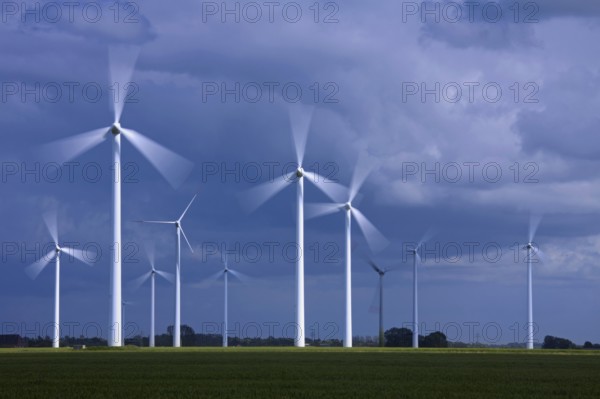 Spinning blades of wind turbines at the wind farm against stormy skies