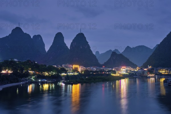 View of Yangshuo town illuminated in the evening with dramatic karst mountain landscape in