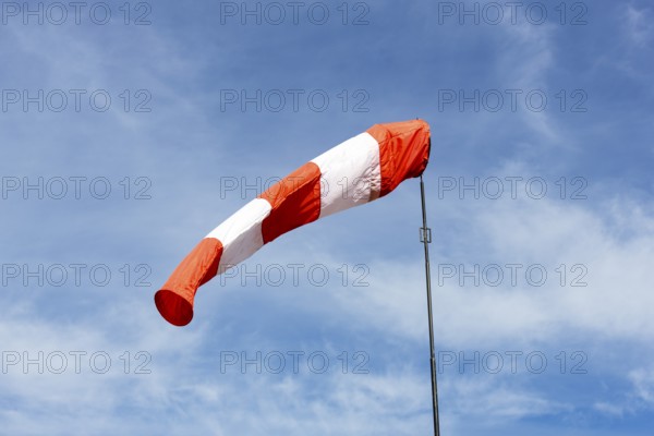 White-red windsock against blue sky, cloudy, wind vane, Germany, Europe