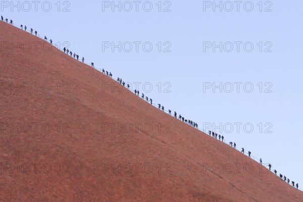 A long queue of people climbs the steep red rock face of Uluru (Ayers Rock), Australia, Oceania