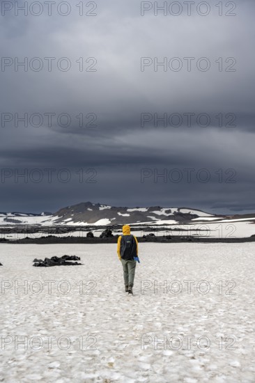 Hikers in snow-covered volcanic landscape with volcanic sand and petrified lava, crater of Askja