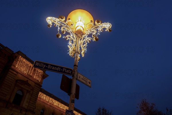 Christmas decorated street lamp on Willy-Brandt-Platz, behind it central station, Magdeburg,