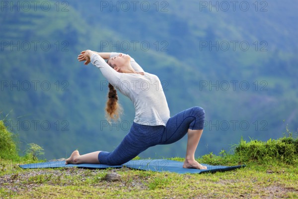 Yoga outdoors, sporty fit woman practices Hatha yoga asana Anjaneyasana, low crescent lunge pose