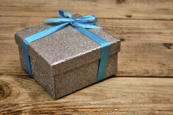 Gift birthday Christmas present concept, silver gift box with blue ribbon on old wooden background