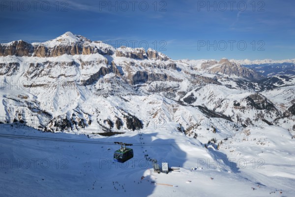 View of a ski resort piste with people skiing in Dolomites in Italy with cable car ski lift. Ski