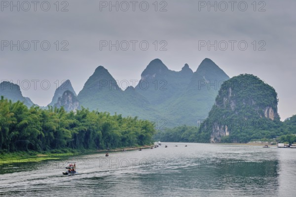 Tourist boats on Li river with dramatic karst mountain landscape in the background. Yangshuo,