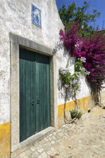 Picturesque alley, houses decorated with flowers in the medieval village of Óbidos, Portugal,