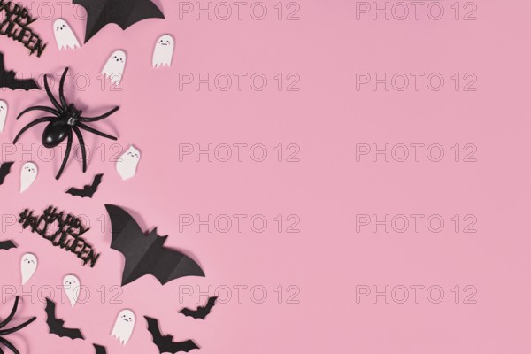 Halloween flat lay with bats, spiders, Happy Halloween text and cute ghosts on side of pink