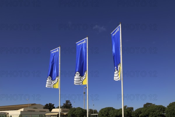Company flags with logo Bibendum figure flying outside, Michelin factory and research