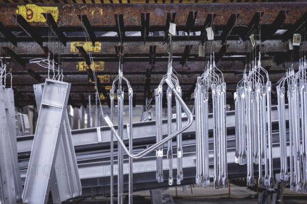 Finished galvanised steel parts lie in the factory hall of a surface finishing factory of the
