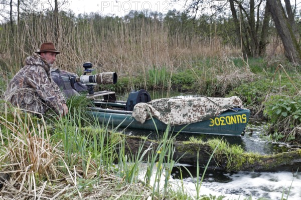 A canoe with camouflaged camera in a swamp, surrounded by vegetation and quiet nature, boat of a