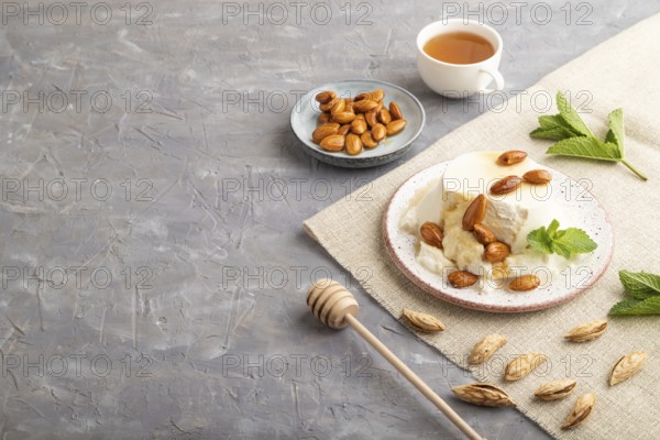 Ricotta cheese with honey and almonds on gray concrete background and linen textile. side view,