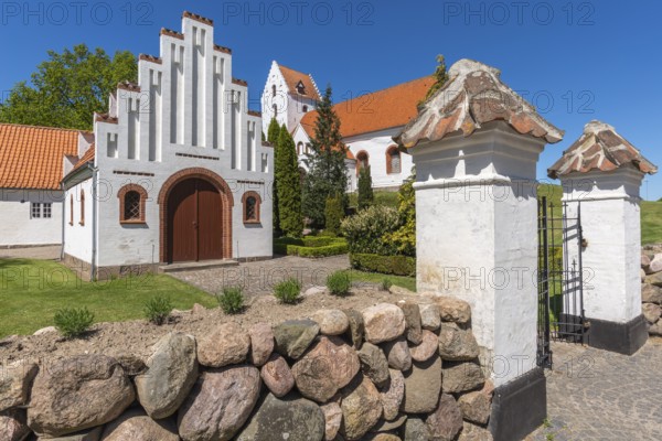 Lindelse Kirke, typical Danish church from 1830, whitewashed, red tiled roof, hill, entrance gate,