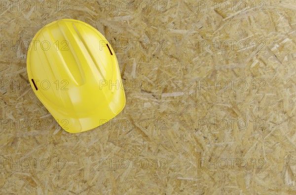 Overhead of yellow hard hat on particleboard with room for text