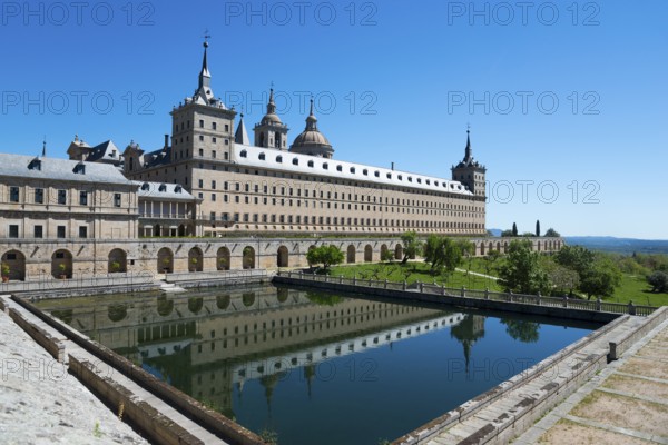 Historic monastery with reflection in the water trough under a blue sky, Real Sitio de San Lorenzo