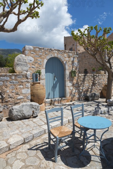 Inviting hotel terrace with stone walls and a blue sky with table and chairs in the shade,